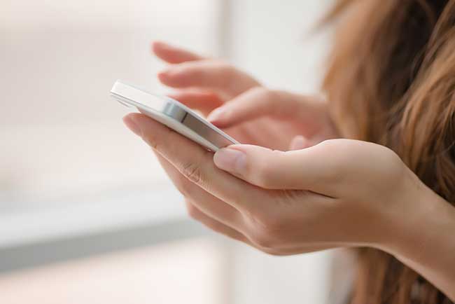 Femme naviguant sur internet tenant un smartphone dans les mains